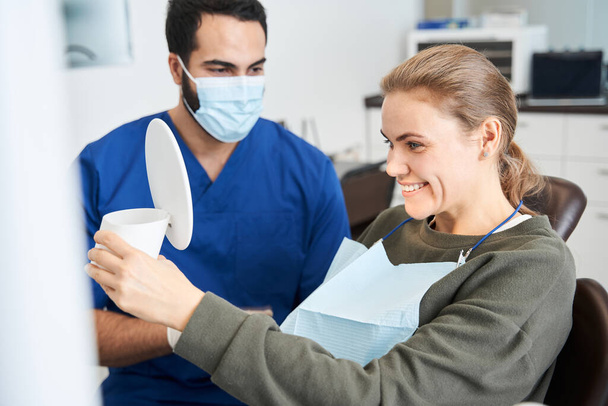 Dentist holding mirror while checking final result - Foto, immagini
