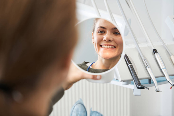 Attractive caucasian lady checking her beautiful smile in mirror - Fotoğraf, Görsel