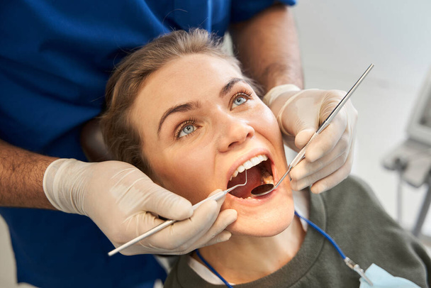 Dentist examining woman mouth with the mirror - Φωτογραφία, εικόνα