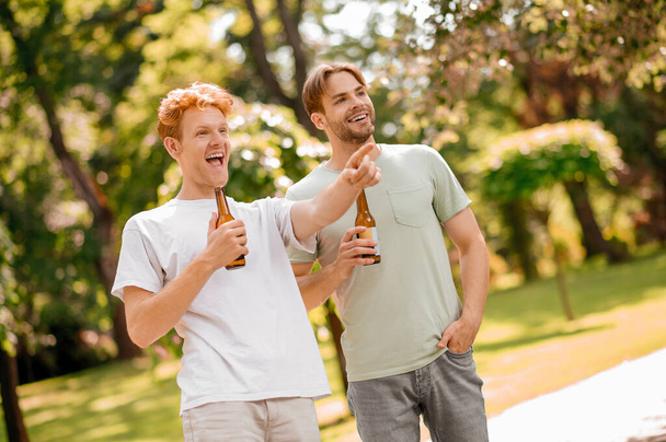 Δύο φίλοι με μπύρα διασκεδάζουν στο πάρκο - Φωτογραφία, εικόνα