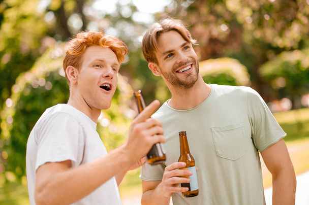Les gars souriants avec des bouteilles voir quelque chose d'intéressant - Photo, image