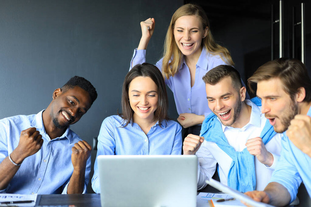 Glückliche Geschäftsleute lachen neben Laptop im Büro. Erfolgreiche Teamkollegen scherzen und haben Spaß bei der Arbeit. - Foto, Bild