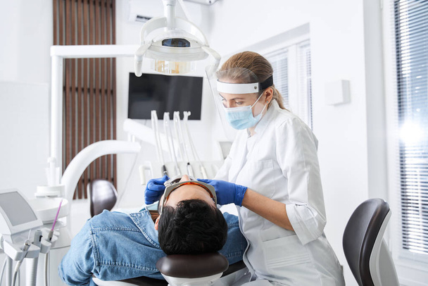 Amichevole dentista regolare qualcosa mentre si lavora in clinica dentale - Foto, immagini