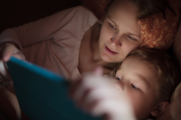 Mother and son with pad in bed at night - Photo, Image