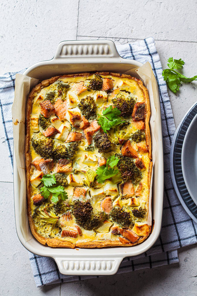 Quiche pie with salmon and broccoli in baking dish, top view. - Foto, afbeelding