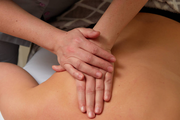 Gros plan de mains masseuses habiles donnant massage soulagement des douleurs dorsales à une jeune cliente dans un cabinet médical - Photo, image