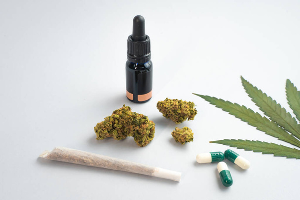 CBD oil, capsules and hemp buds on white background. Organic and natural hemp-based cosmetic and beauty products. Medical cannabis concept. Alternative medicine. Copy space for text. - Photo, image