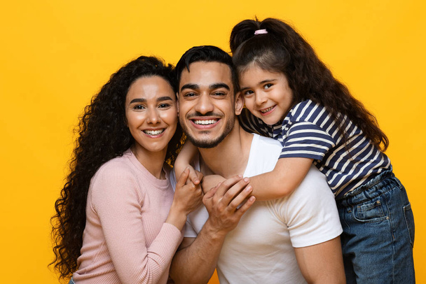 Glückliches Familienporträt. Nahaufnahme von lächelnden Eltern aus der Mittelschicht mit kleiner Tochter, - Foto, Bild
