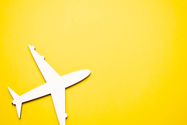 Miniature toy airplane on yellow background. Trip by airplane. - Zdjęcie, obraz