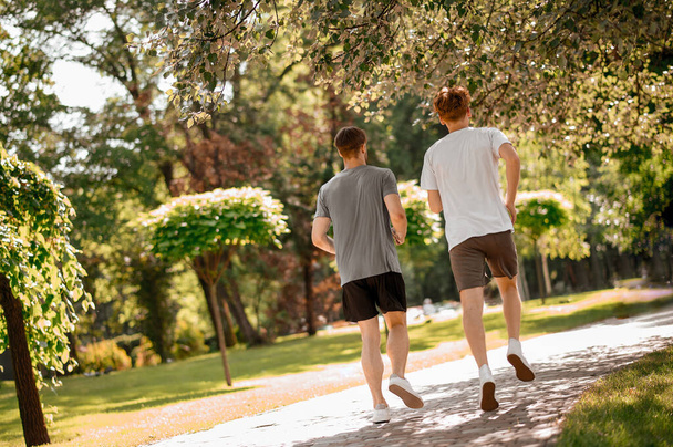 Вид со спины парней, бегущих в парке - Фото, изображение