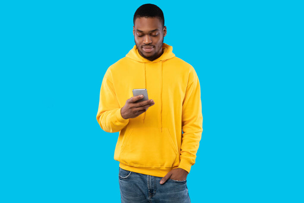 Black Man Using Smartphone Texting In Social Media, Blue Background - Foto, Imagen