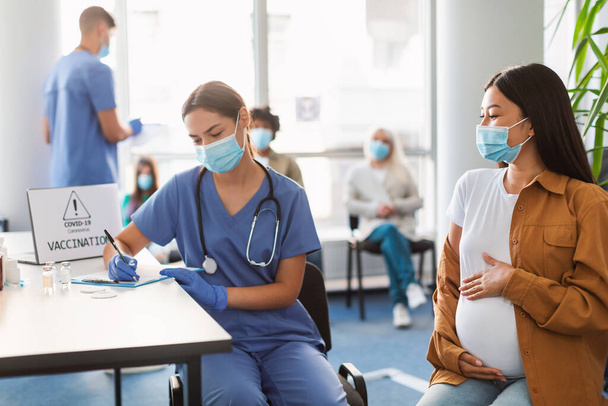 Doctor teniendo cita para la vacunación a la sonriente mujer embarazada - Foto, Imagen