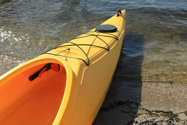 Yellow kayak on beach near river, closeup. Summer camp activity - Foto, imagen