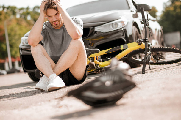 Unhappy guy sitting on road touching head - Photo, Image