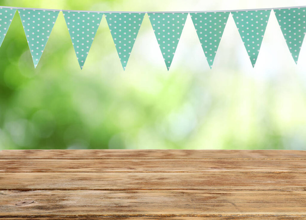 Empty wooden table and decorative bunting flags outdoors - Foto, immagini