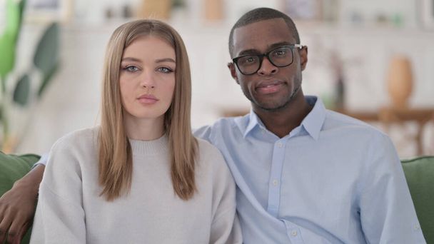 Serious Interracial Couple Looking at the Camera, Home - Foto, Bild