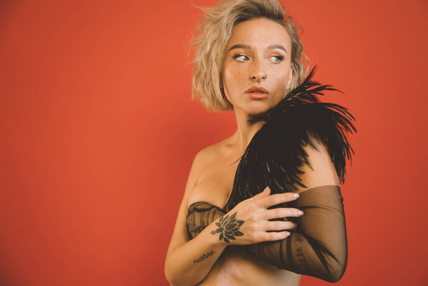 Naked woman wearing boa looking over red background - 写真・画像