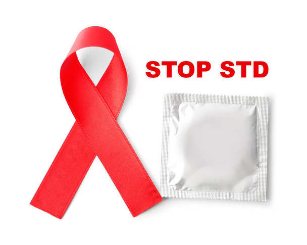 Red awareness ribbon, condom and text Stop STD on white background, top view  - Foto, imagen
