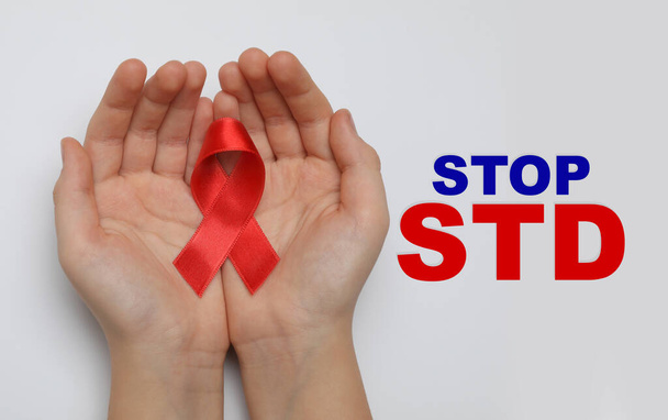 Young woman holding red awareness ribbon on white background, top view. Stop STD  - Photo, image