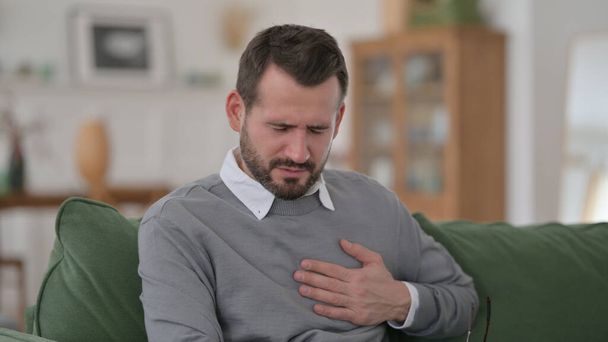 Mann mittleren Alters hat auf Sofa plötzlichen Herzschmerz - Foto, Bild