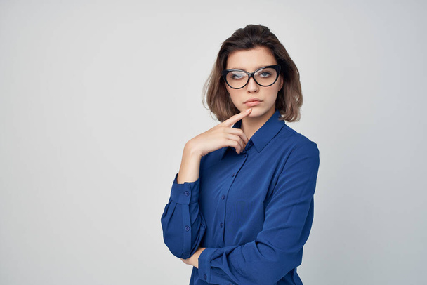 Üzleti nő kék ingben visel csillogó szemüveg pózol fény háttér - Fotó, kép