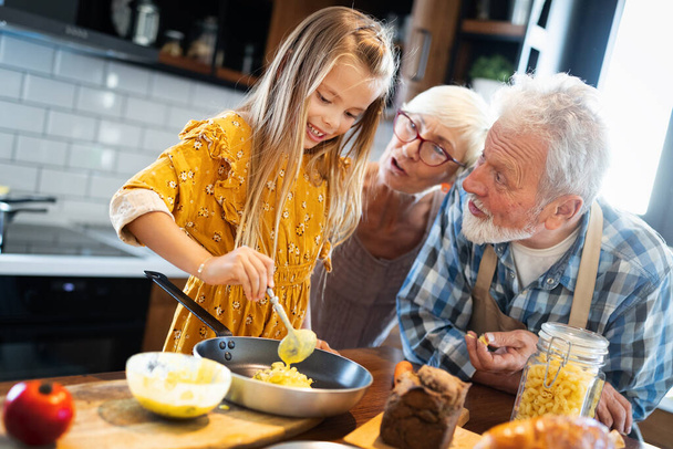 Happy elderly couple having breakfast with their grandchildren at home - Photo, image