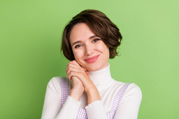 Photo of young attractive woman happy positive smile hands touch cheek isolated over green color background - Фото, зображення