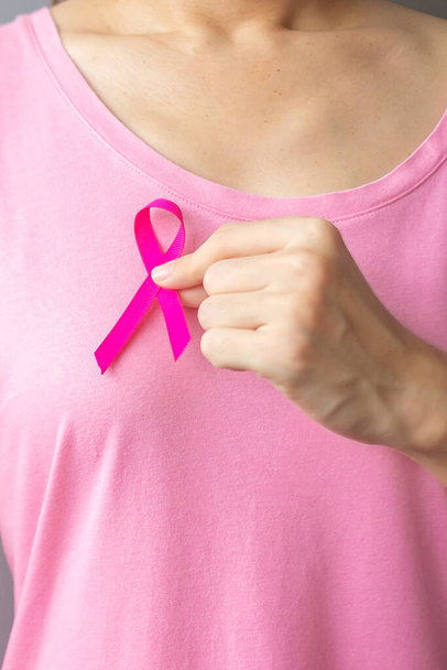 Οκτώβριος Μαστού μήνα ευαισθητοποίησης του καρκίνου του μαστού, ηλικιωμένη γυναίκα σε ροζ T-shirt με το χέρι κρατώντας ροζ κορδέλα για την υποστήριξη των ανθρώπων που ζουν και ασθένεια. Παγκόσμια Ημέρα κατά του Καρκίνου, Γυναίκες, Μητέρες και Γυναίκες - Φωτογραφία, εικόνα