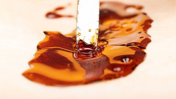 scrape off the marijuana concentrate cannabis wax with parchment paper - 写真・画像