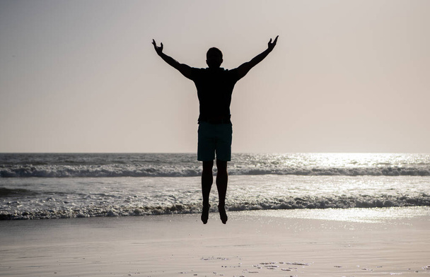 чувствовать свободу. молодой и свободный. спортсмен прыгает в океан. утренняя тренировка. - Фото, изображение