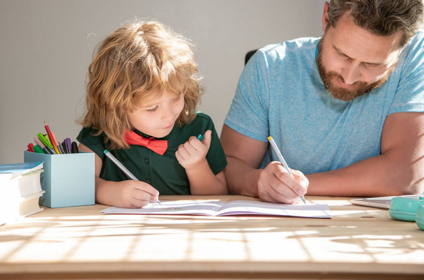 padre barbudo escribiendo tareas escolares con su hijo en el aula, de vuelta a la escuela - Foto, imagen