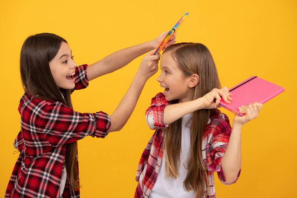 meninas adolescentes felizes em camisa quadriculada brincando com cadernos, emoções positivas - Foto, Imagem