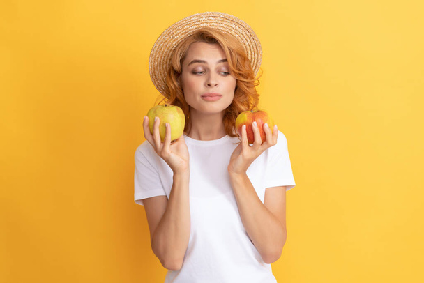 μια γυναίκα με ψάθινο καπέλο που τρώει υγιεινό φαγητό. υγεία των νέων. φυσικό βιολογικό νωπό μήλο - Φωτογραφία, εικόνα