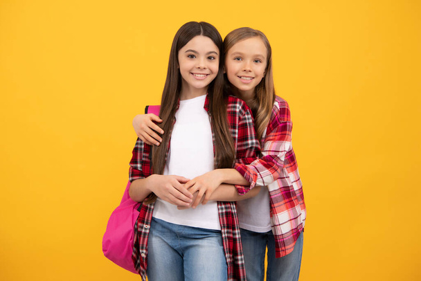 cute embracing children in casual checkered shirt carry backpack, college - Foto, afbeelding