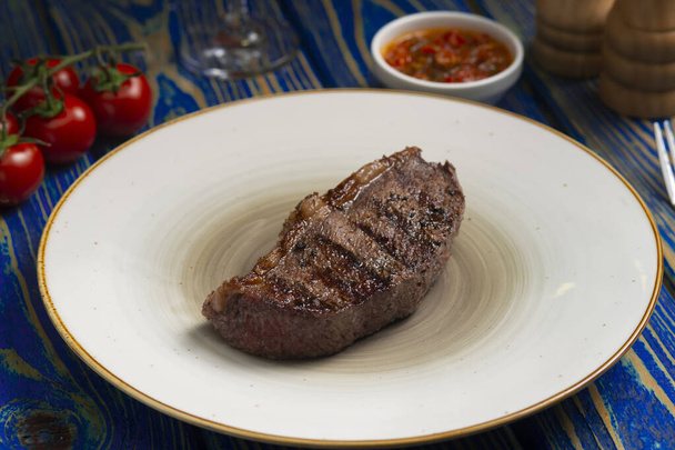 Roasted steak ,cherry tomatoes, salt and pepper on blue  wooden table. - Foto, Bild