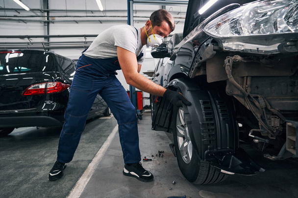Car mechanic is removing wheel arch cover - Valokuva, kuva