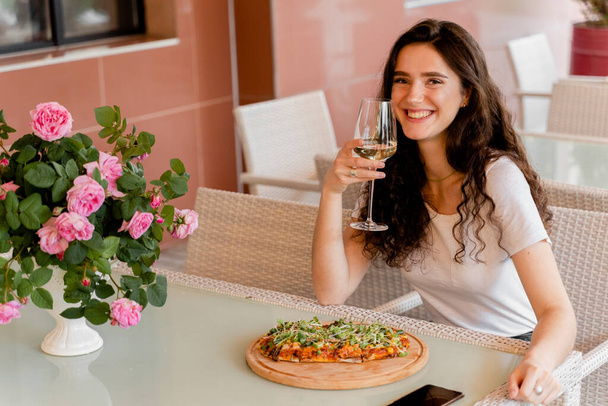 Girl with pinsa romana in cafe on summer terrace. Young woman eating pinsa and drinking wine. - Photo, Image