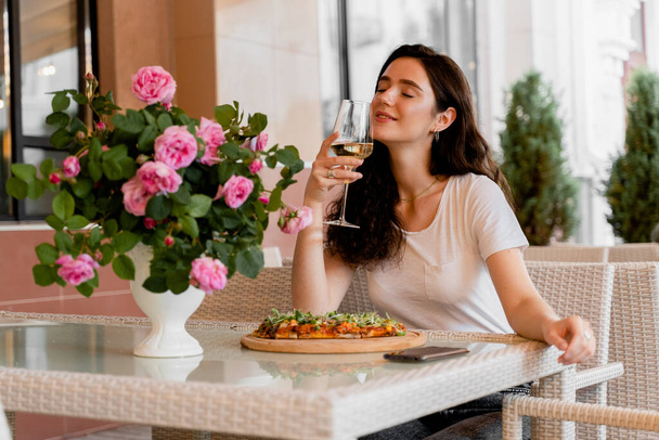 Chica con pinsa romana en la cafetería en la terraza de verano. Mujer joven comiendo pinsa y bebiendo vino. - Foto, Imagen