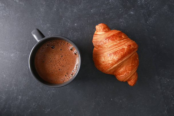 Fresh baked croissant, mug of expresso on dark concrete table. Cup of hot coffee, buns, rolls close up. Bakery food, French breakfast, morning menu, cafe concept. Top view - Foto, afbeelding