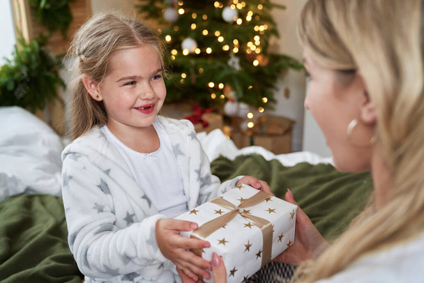 Küçük kız annesine Noel hediyesi veriyor. - Fotoğraf, Görsel