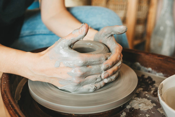 Vrouwelijke keramiek maker of pottenbakker werken met aardewerk wiel in de werkplaats. Creatieve mensen en ambachtelijke aardewerk klasse concept. - Foto, afbeelding