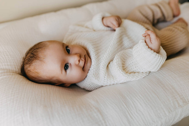 Bebé vistiendo ropa de invierno, un suéter de punto cálido y pantalones, sonriendo, mirando a la cámara. - Foto, Imagen