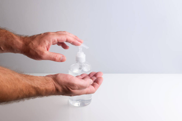 Hombre manos usando dispensador de gel hidroalcohólico para desinfectar contra virus y mantenerse saludable - Foto, Imagen
