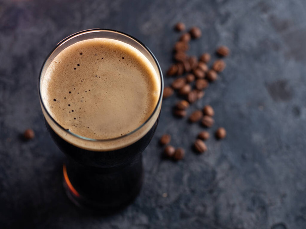 Top view of a glass of dark stout or porter beer with coffee added. Dark background - Zdjęcie, obraz