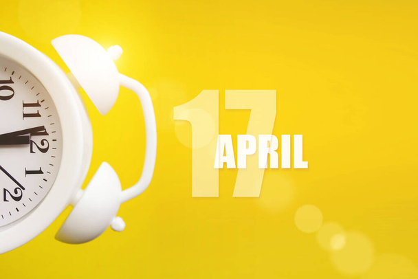 Le 17 avril. Jour 17 du mois, date du calendrier. Réveil blanc sur fond jaune avec jour calendrier. Printemps mois, jour de l'année concept - Photo, image
