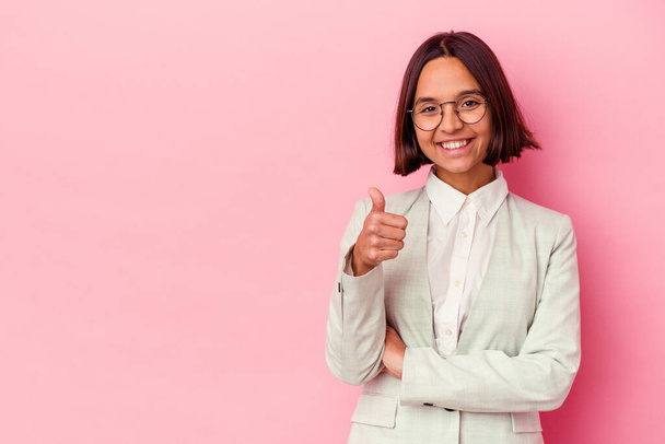 Young mixed race woman wearing a green suit isolated on pink background smiling and raising thumb up - Photo, Image