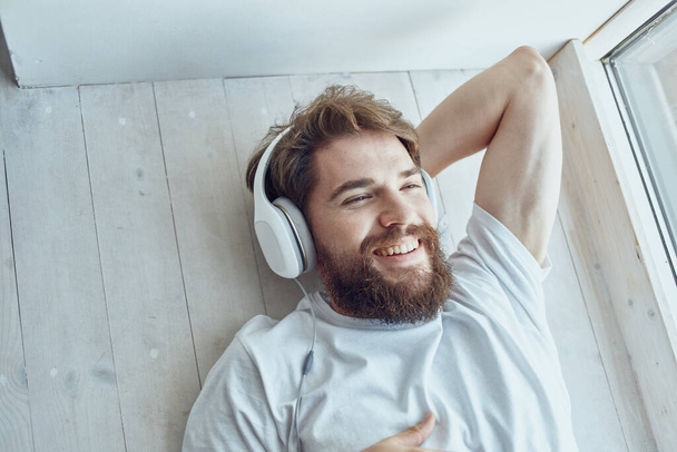 cute man lying near the window wearing headphones hipster - Photo, Image
