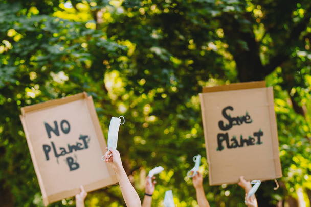 Closeup view of a homemade signs, saying there is no planet b, held by eco-activists during a march against climate change and keeping medical mask in their hands on pandemic time. - Photo, Image