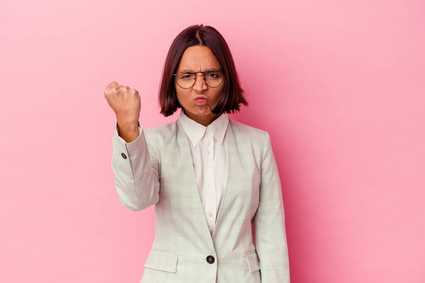 Young mixed race woman wearing a green suit isolated on pink background showing fist to camera, aggressive facial expression. - Photo, Image