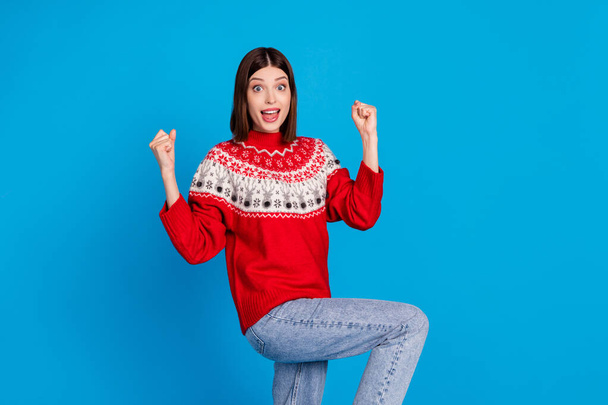Photo portrait woman amazed gesturing like winner in xmas sweater isolated vivid blue color background - Foto, imagen